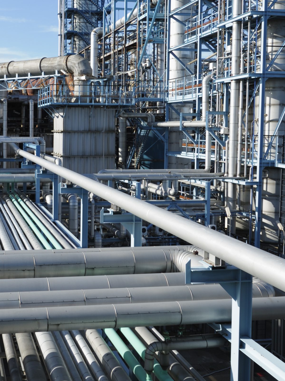Refinery pipework and pressure vessels under a blue sky